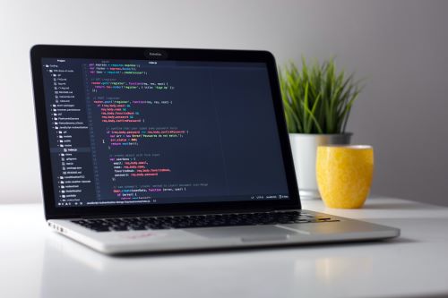 Image description: a laptop computer is sitting open on a white table with code on the screen.