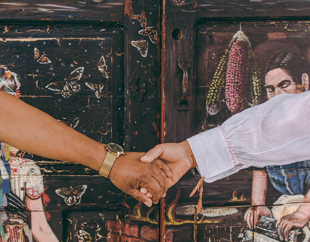 image of people holding hands in from of mural