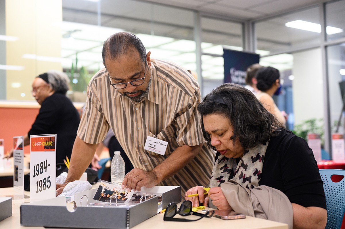 Michael Thomas (ENG 1975) and Audrey Sykes (MCS 1981) identify alumni in a 1985 photo album.