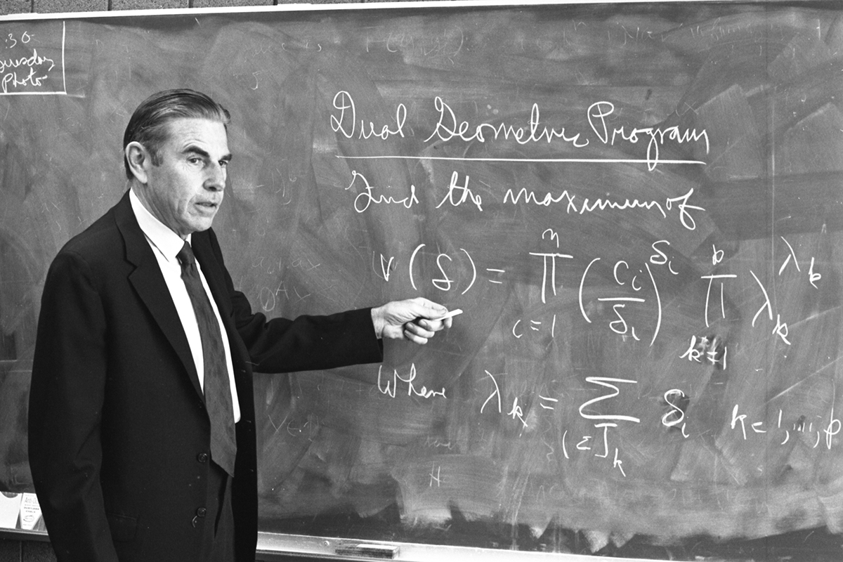 Richard Duffin in front of mathematical calculations on a chalkboard.