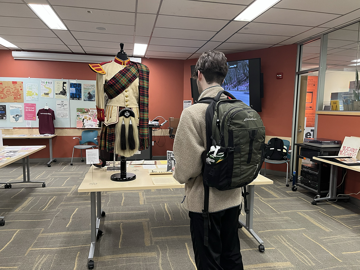 An attendee examines items from the Kiltie Band, including a uniform from the 1970s.