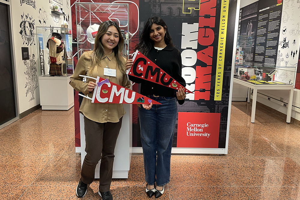Students pose with pennants in front of the Room to Imagine exhibit.