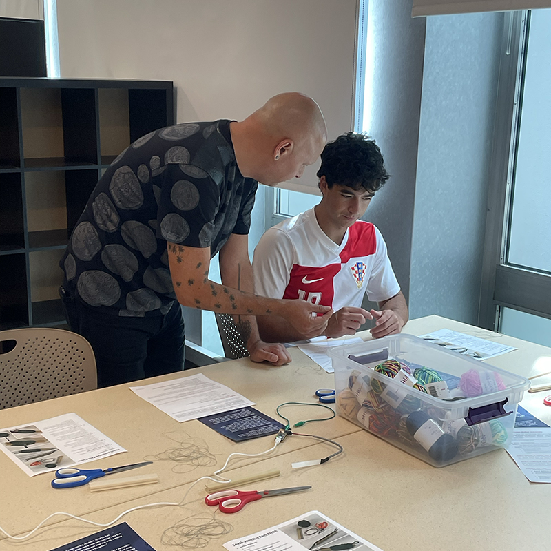 IDeATe Academic Coordinator Ryan McKelvey walks a student through part of a hands-on e-textile skillshare during the information session.