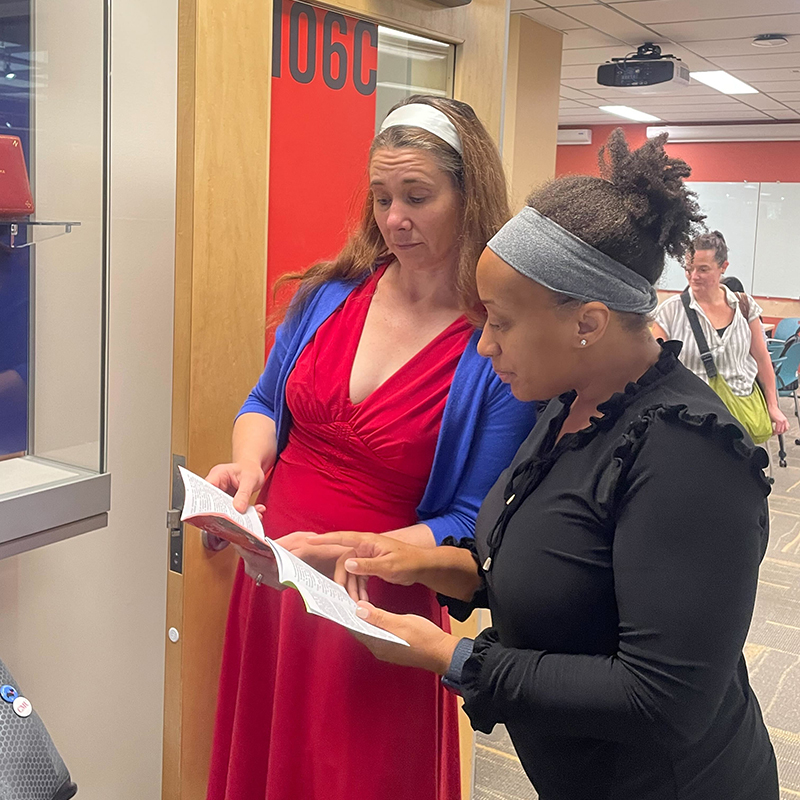 Executive Assistant Anne Kramer and Development Associate Najah Magloire flip through pocket-sized copies of the U.S. Constitution.