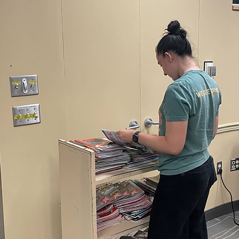 A student searches through the pages of a magazine to choose imagery for the activity.