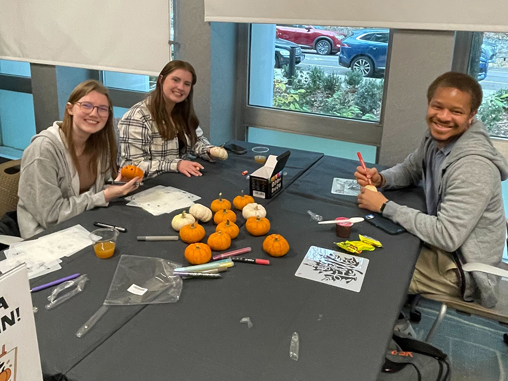 A group of attendees poses with their pumpkins for a photo.