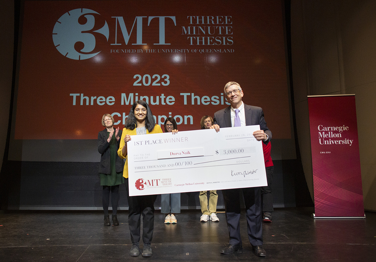 1st place winner, Durva Naik is presented a check by Provost Jim Garrett.