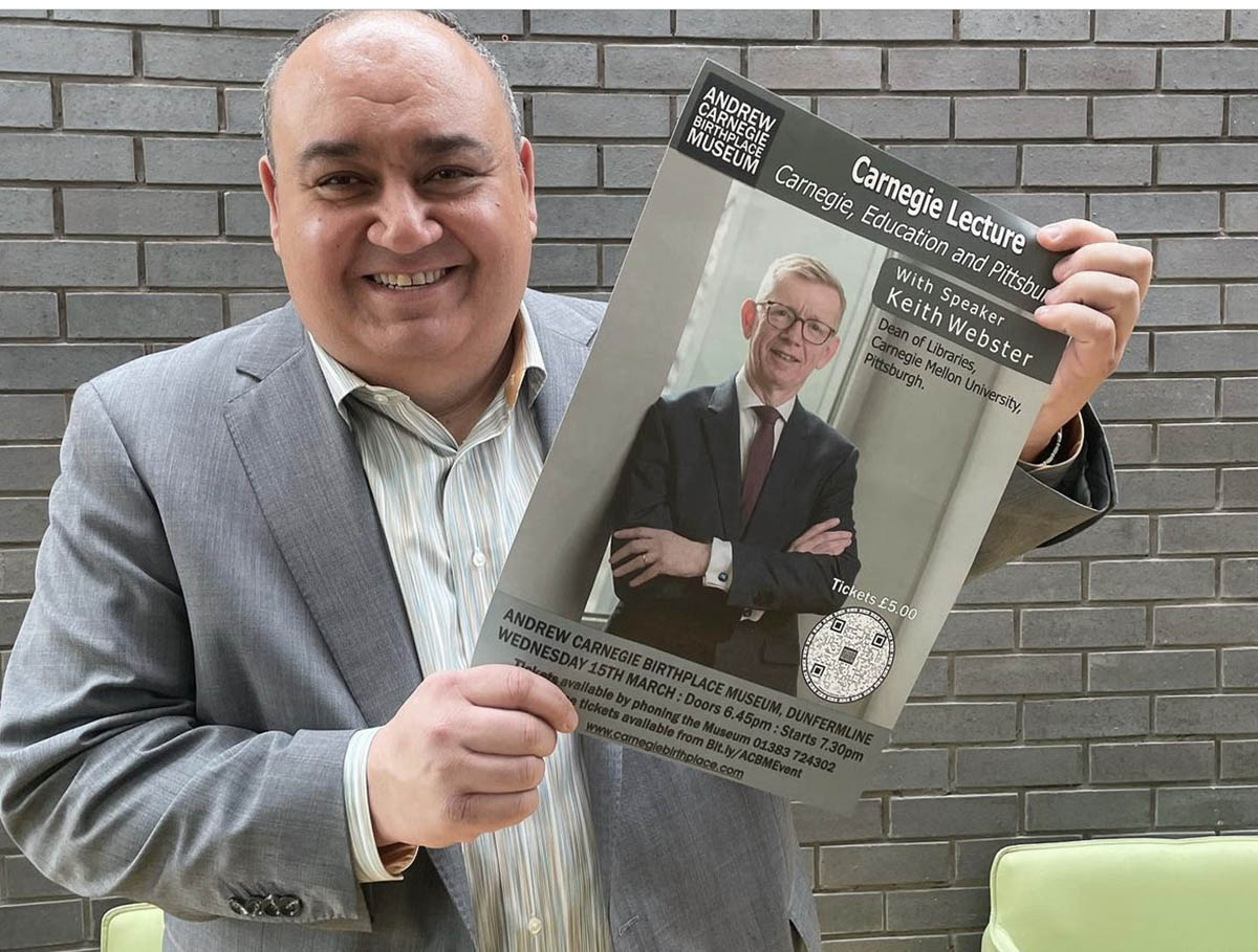 CMU's Vice President for University Advancement Scott Mory poses with a poster for Webster's Carnegie Lecture.